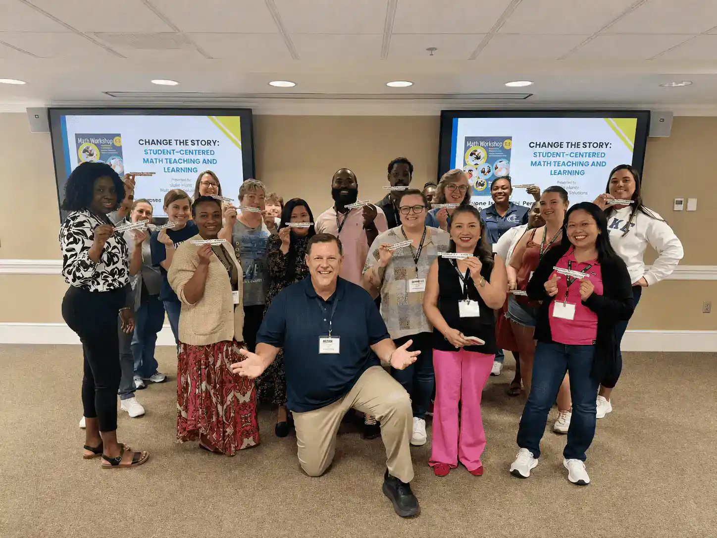 Group of diverse professionals at CTLG conference with presentation screens.