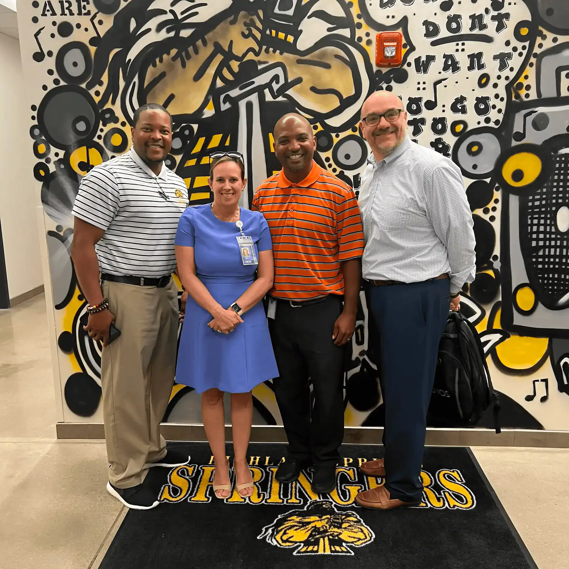 Group of four professionals standing in front of CTLG mural.